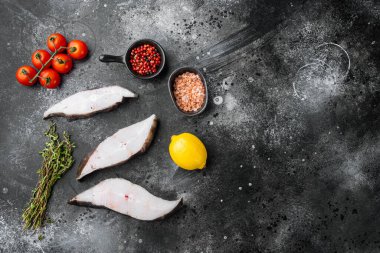 Dilimlenmiş Halibut balığı seti, malzeme ve biberiyeli, siyah taş masa zemininde, üst görünüm düz, metin için kopyalama alanı