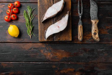 Çiğ balık kesim seti, malzemeler ve biberiye bitkileri ile, eski koyu ahşap masa arka planı, üst görünüm düz, metin için kopya alanı ile