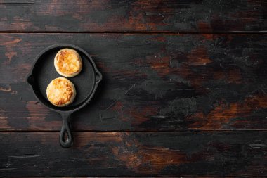 Peynirli kekler dökme demir tavada tatlı krepler, üst manzara düz, siyah ahşap masa zemininde, metin için kopyalama alanı ile