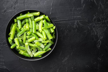 Donmuş yeşil fasülye seti, kasede, siyah taş zemin üzerinde, üst görünüm düz, metin için kopyalama alanı ile