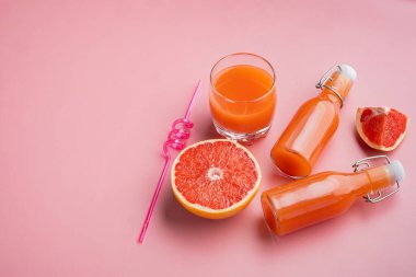 Taze greyfurtlar ve bir bardak greyfurt suyu seti, pembe desenli yaz arkaplanı, metin için fotokopi alanı