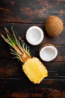 Taze egzotik meyveler, ananas ve hindistan cevizi seti, eski siyah ahşap masa zemininde, üst manzara düz yatıyordu.