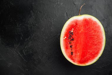 Yarı karpuz kesim seti, siyah taş masa arkaplanı, üst görünüm düz, metin için kopyalama alanı ile
