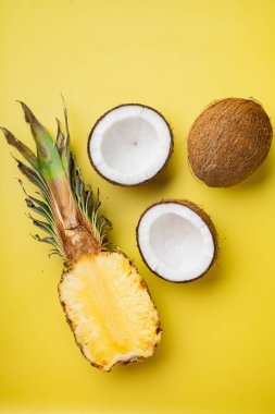 Egzotik ve tropikal meyvelerden oluşan yaratıcı düzen, ananas ve hindistan cevizi seti, sarı desenli yaz arkaplanı, üst manzara düz