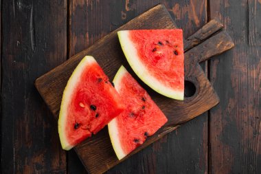 Dilimlenmiş karpuz seti, eski koyu ahşap masa zemininde, üst manzara düz.