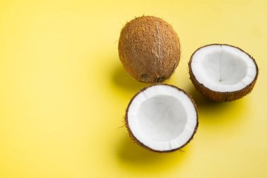 Yarım set hindistan cevizi, sarı desenli yaz arkaplanı, üst görünüm düz yatay, metin için kopyalama alanı