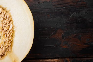 Olgun, taze, sarı kavun yarım set, eski koyu ahşap masa arkaplanı, üst görünüm düz, metin için kopyalama alanı ile