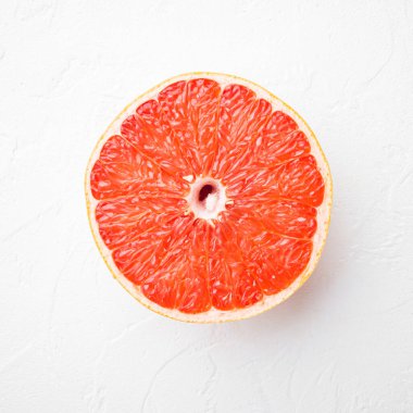 Olgun bir dilim pembe greyfurt narenciye seti, beyaz taş masa arkaplanı, kare format, üst görünüm düz yatıyordu