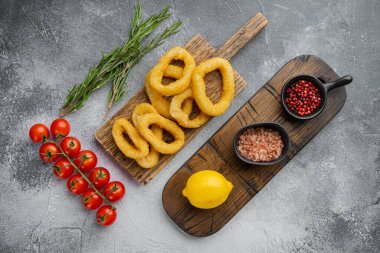 Mürekkep balığı halkaları ya da ekmek kırıntılarında soğan, servis panosunda, gri taş masa zemininde, üst görünüm düz yatıyordu