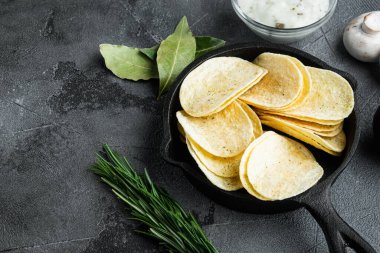 Çıtır patates cipsi. Patates dilimleri, deniz tuzu setiyle kızartılmış, soslu, gri taştan arka planda.