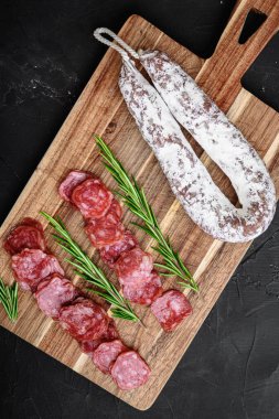 Fuet salam sosis dilimlenmiş ve tüm sosis siyah desenli yüzey, üst görünüm.