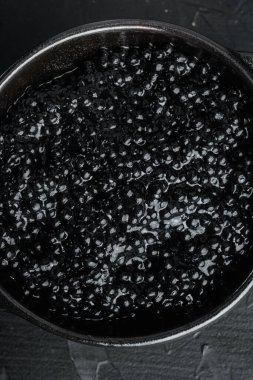 Siyah havyar kasesi, siyah arka planda, üst manzara düz.