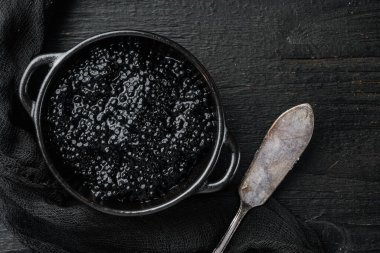 Siyah havyar kasesi, siyah ahşap masa zemininde, üst manzara düz.