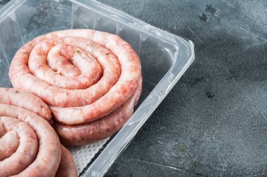 Ham spiral sosis seti, gri arkaplanda, plastik pakette, metin kopyalanacak yer