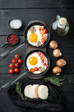 Kızarmış yumurta ve kiraz domatesli ve kahvaltıda demir tavada ekmek, siyah ahşap masa zemininde, üst manzara düz