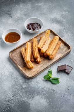 Tipik İspanyol çerezi churros, kızarmış hamur pastası genellikle çikolata karamelli acı sos setiyle servis edilir, gri arka planda.