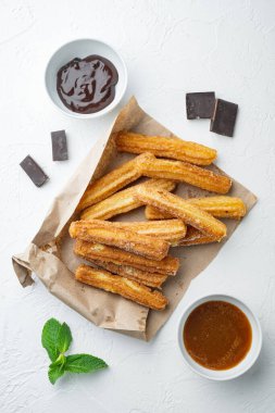 Karamelli Churros, geleneksel İspanyol dişi, beyaz arka planda, düz manzaralı.