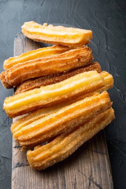 Geleneksel churros çubukları tarçın ve şeker tozu seti, siyah arka planda.