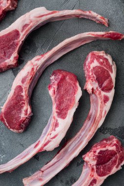 Taze kuzu pirzolası. Organik et seti, gri taştan arka planda, üst manzara düz.