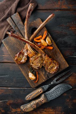 Ev yapımı kuzu pirzolası, sarımsak ve havuç, ahşap servis tahtasının üzerinde, eski, ahşap masa zemininde, üst manzara düz