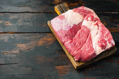 Çiğ parça mermer biftek göğüs eti seti, eski koyu ahşap masa arkaplanı, metin için kopyalama alanı ile