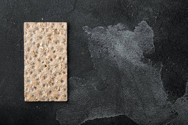 Ayçiçeği, chia ve susam tohumlu kepekli ekmek yığını, siyah taş masa arkaplanı üzerinde, üst görünüm düz, metin alanı için kopyalama alanı