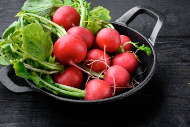 Küçük turp seti, siyah ahşap masa arkaplanı.