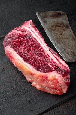 Çiğ et kulübü bifteği. Kurumuş, siyah ahşap masa arkasında.