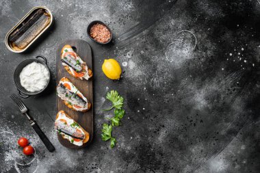 Sardalyalı sandviç, füme balık seti, siyah taştan masa arkaplanı, en üstteki düz görünüm, metin için kopyalama alanı