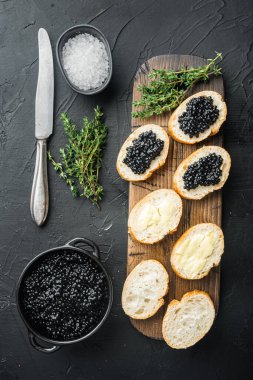 Siyah arka planda, siyah havyar ve tereyağlı sandviçler, düz manzaralı.