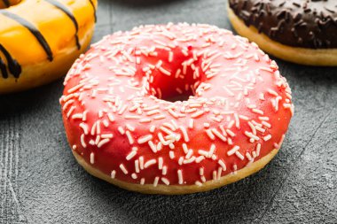 Gri arka planda pembe çilekli çörekler.