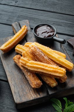 Çurros, siyah ahşap masa zeminine pudra şekeri serpiştirilmiş.