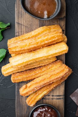 Çikolatalı Churros, geleneksel İspanyol dişi, siyah arka planda, üst manzara düz.