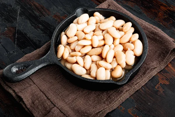 White canned beans set, in cast iron frying pan, on old dark  wooden table background
