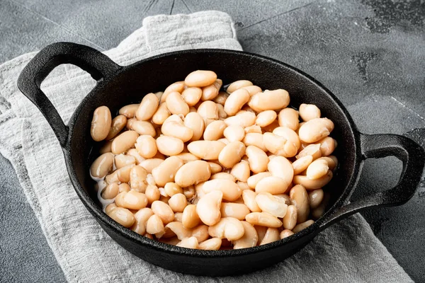 White canned beans set, in cast iron frying pan, on gray stone background