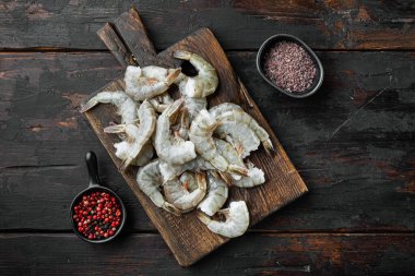 Kral karideslerdeki çiğ kabuk seti, ahşap kesim tahtası, eski, siyah ahşap masa, üst manzara düz yatıyordu