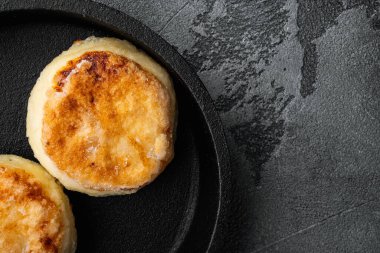 Fırınlanmış süzme peynirli krepler dökme demir tavaya, üst görünüm düz yere, gri taş masa arka planına, metin için kopyalama alanı ile