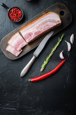 Tütsülenmiş domuz pastırması, siyah arka planda otlarla kaplı koca bir levha, metin için yeri olan üst manzara..