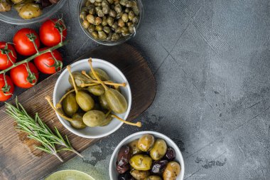 Akdeniz zeytinleri ve otlu kapari, gri arka planda, metin için kopyalama alanı ile düz yatar