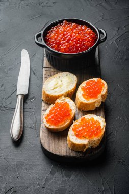 Siyah arka planda kırmızı balık havyarlı sandviç.