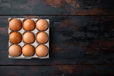 Kahverengi yumurtalar karton kutu tepsisinde, eski koyu ahşap masa arkasında, üst görünüm düz, metin kopyalama alanı için yer var.