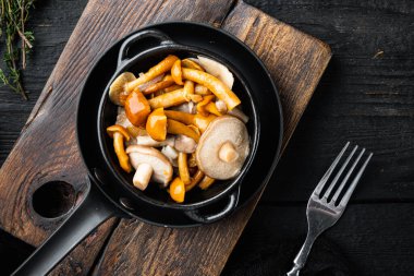 Salamura mantar seti, siyah ahşap masa arkaplanı, üst görünüm düz yatıyordu