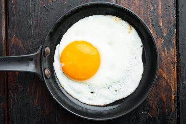 Kızarmış yumurta ve kiraz domatesli ve kahvaltıda demir tavada ekmek, eski koyu ahşap masa zemininde, üst manzara düz