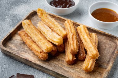 Karamelli Churros, geleneksel İspanyol dişi, gri arka planda.