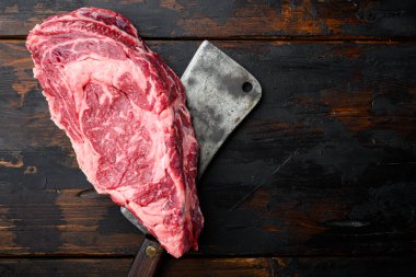 Organik mermer et, biftek ve baharat seti, pirzola kesimi, eski kasap bıçağı, eski siyah ahşap masa arka planı, üst görünüm düz, metin için kopyalama alanı