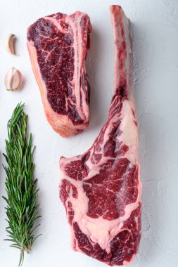 Çiğ taze baltayla kurutulmuş mermer biftek seti, beyaz taştan arka planda, düz manzaralı.