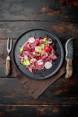 Leziz taze mermer et aperatifleri - sığır carpaccio seti, turp ve garnet, tabak üzerinde, eski siyah ahşap masa zemininde, üst görünüm düz, metin için kopya alanı ile