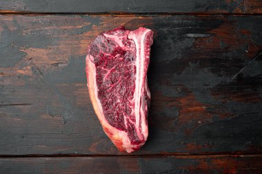 Marble sığır eti, Black Angus biftek seti, kulüp bifteği, eski koyu ahşap masa arkaplanı, üst görünüm düz, metin alanı için kopya alanı