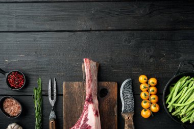 Pişmemiş çiğ et, sette kemikli, ızgara malzemeli, siyah ahşap masa zemininde, üst görünümü düz, metin için kopyalama alanı olan kırmızı et.