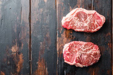 Üst bıçak organik et, çiğ mermer biftek, koyu ahşap kırsal masa, üst manzara yazı için yer.
